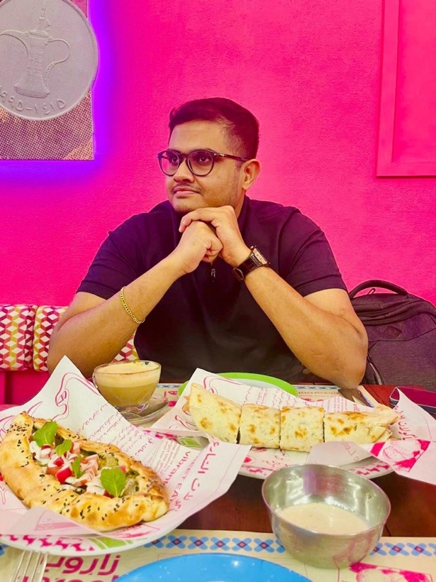 Enura at a pink-walled restaurant with a table of food